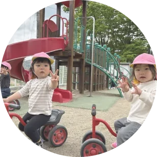 園庭で三輪車に乗る子どもたち
